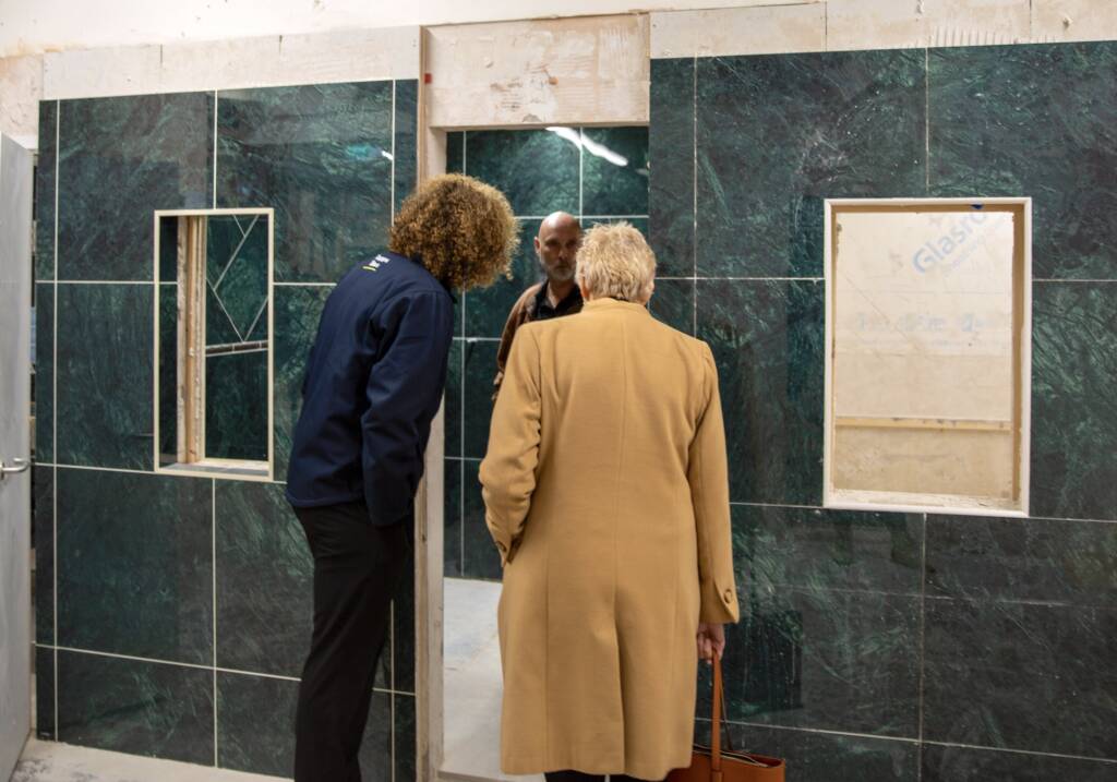 This is a photo of the Topps Tiles education partnership launch where three people are looking at some tiling work.