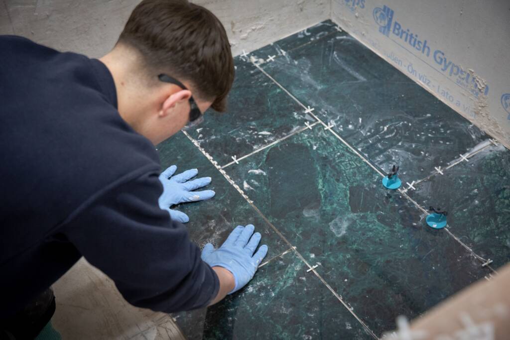 This photo depicts an LCB student working on some floor tiles.