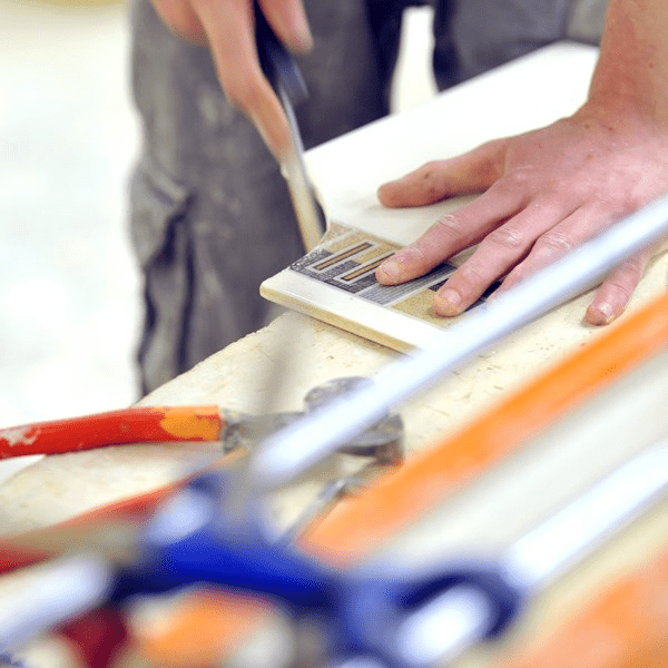 This image depicts someone using tools to reshape a tile.