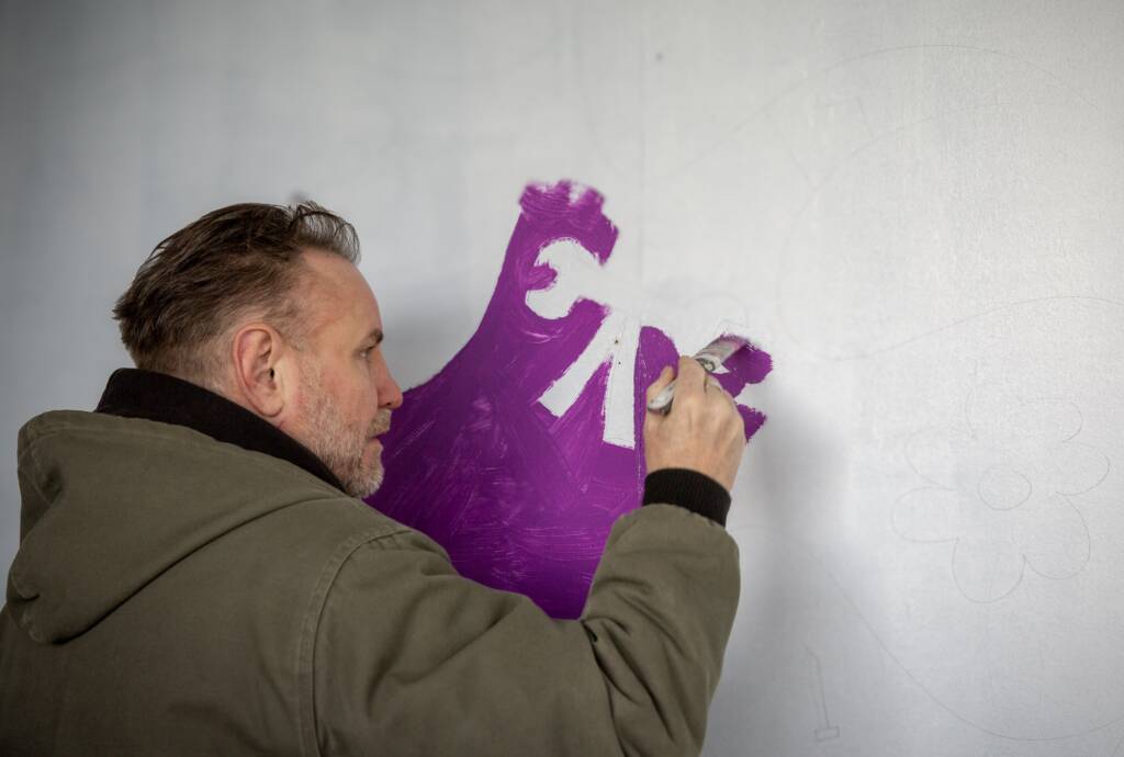 This is a photo of Artist Nicolas Dixon working on the mural.