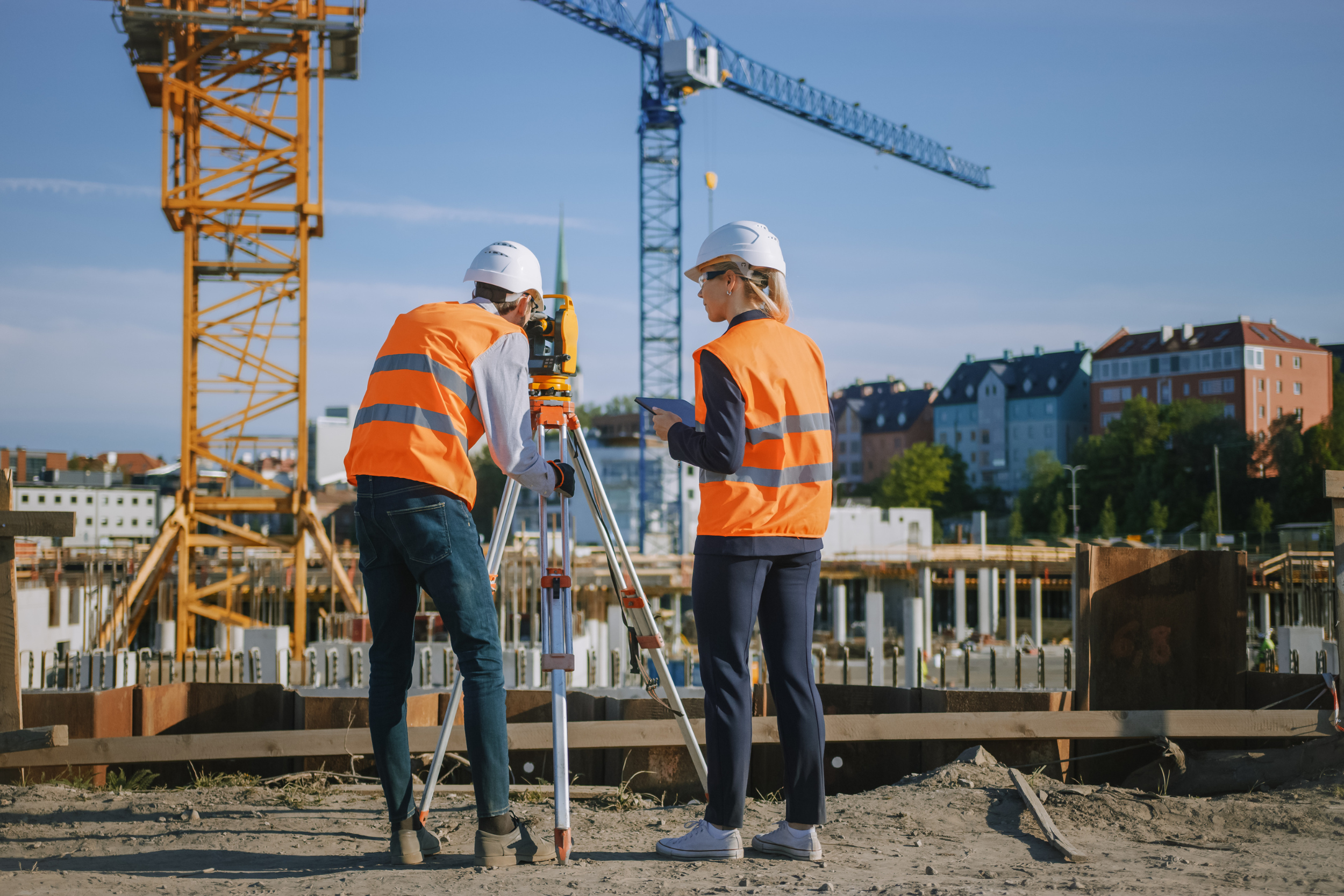This photo depicts two students using surveying equipment on a construction site.
