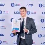 This photo depicts a student with their award against the LCBU photo wall.
