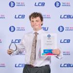 This photo depicts a student with their award against the LCBU photo wall.