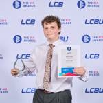 This photo depicts a student with their award against the LCBU photo wall.