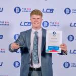 This photo depicts a student with their award against the LCBU photo wall.