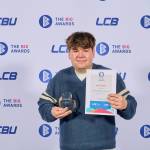 This photo depicts a student with their award against the LCBU photo wall.