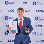 This photo depicts a student with their award against the LCBU photo wall.