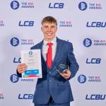 This photo depicts a student with their award against the LCBU photo wall.