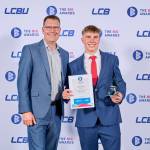 This photo depicts a student with their award against the LCBU photo wall.