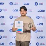 This photo depicts a student with their award against the LCBU photo wall.