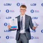This photo depicts a student with their award against the LCBU photo wall.