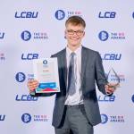 This photo depicts a student with their award against the LCBU photo wall.