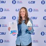 This photo depicts a student with their award against the LCBU photo wall.