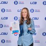 This photo depicts a student with their award against the LCBU photo wall.