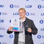 This photo depicts a student with their award against the LCBU photo wall.
