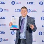 This photo depicts a student with their award against the LCBU photo wall.