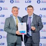 This photo depicts a student with their award against the LCBU photo wall.