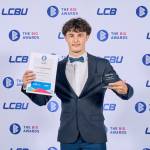 This photo depicts a student with their award against the LCBU photo wall.