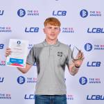 This photo depicts a student with their award against the LCBU photo wall.