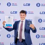 This photo depicts a student with their award against the LCBU photo wall.