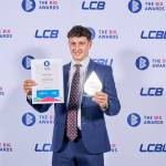 This photo depicts a student with their award against the LCBU photo wall.