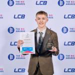 This photo depicts a student with their award against the LCBU photo wall.