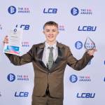 This photo depicts a student with their award against the LCBU photo wall.