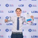 This photo depicts a student with their award against the LCBU photo wall.