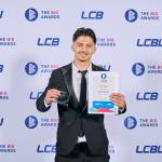 This photo depicts a student with their award against the LCBU photo wall.