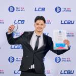 This photo depicts a student with their award against the LCBU photo wall.