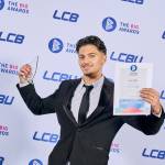 This photo depicts a student with their award against the LCBU photo wall.