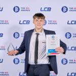 This photo depicts a student with their award against the LCBU photo wall.