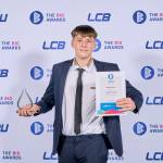 This photo depicts a student with their award against the LCBU photo wall.