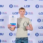 This photo depicts a student with their award against the LCBU photo wall.