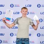 This photo depicts a student with their award against the LCBU photo wall.