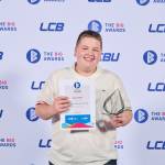 This photo depicts a student with their award against the LCBU photo wall.