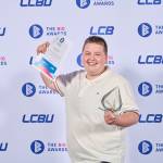 This photo depicts a student with their award against the LCBU photo wall.