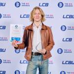 This photo depicts a student with their award against the LCBU photo wall.