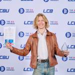 This photo depicts a student with their award against the LCBU photo wall.