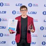 This photo depicts a student with their award against the LCBU photo wall.