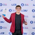 This photo depicts a student with their award against the LCBU photo wall.