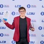 This photo depicts a student with their award against the LCBU photo wall.