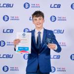 This photo depicts a student with their award against the LCBU photo wall.