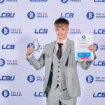 This photo depicts a student with their award against the LCBU photo wall.