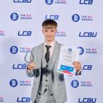 This photo depicts a student with their award against the LCBU photo wall.