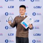 This photo depicts a student with their award against the LCBU photo wall.