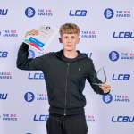 This photo depicts a student with their award against the LCBU photo wall.