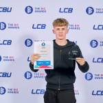 This photo depicts a student with their award against the LCBU photo wall.