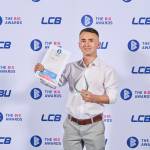 This photo depicts a student with their award against the LCBU photo wall.