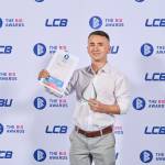 This photo depicts a student with their award against the LCBU photo wall.